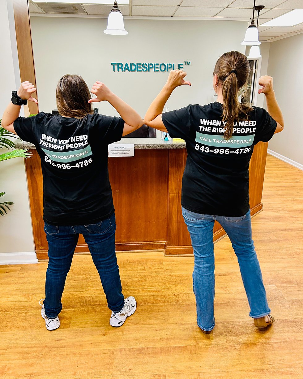 Two TradesPeople staff members at the Charleston office reception, wearing branded shirts that read When you need the right people call TradesPeople
